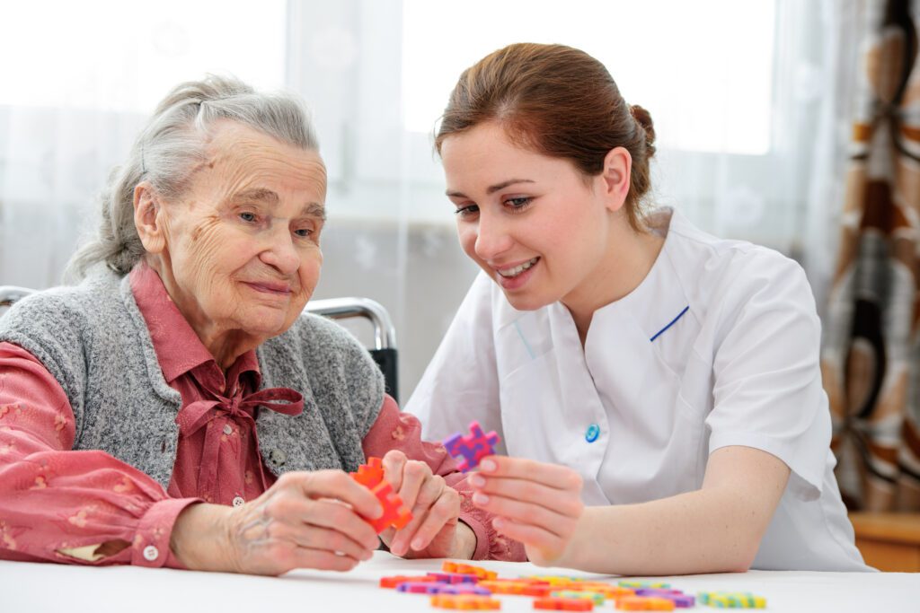 woman nurse and elderly woman patient putting together a puzzle