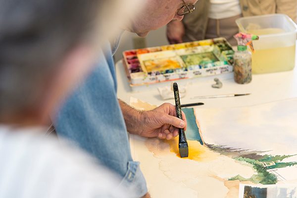 A man using water color at a campus event.